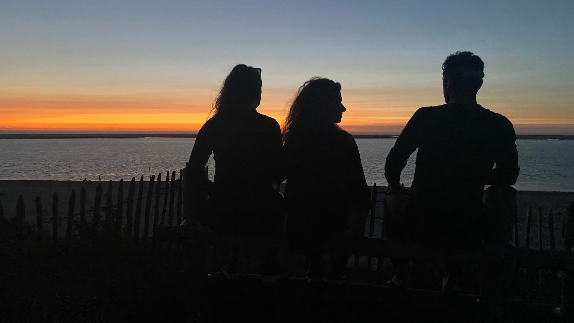Trois participants Old is Gold assis face au coucher de soleil sur la mer